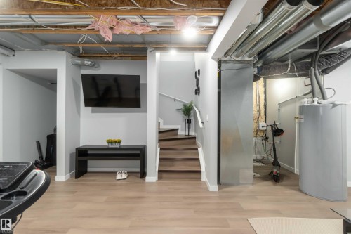 Spacious lower level featuring wood-finish flooring, light grey walls, and exposed ceiling joists - 124 28 Street, Edmonton, AB 