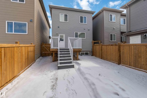 Rear elevation featuring gray horizontal siding and a white deck with lattice railing - 124 28 Street, Edmonton, AB 