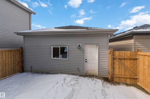 Detached garage with horizontal vinyl siding, a single window, exterior lighting fixture, and a pedestrian door - 124 28 Street, Edmonton, AB 