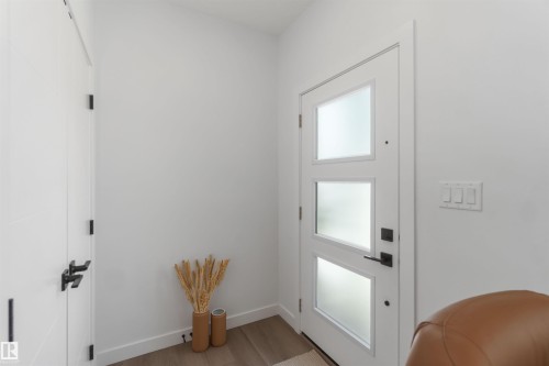Entryway featuring a white door with three frosted glass panels, a second white interior door, and light wood-finish flooring - 124 28 Street, Edmonton, AB 