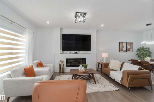 Spacious living area featuring a built-in electric fireplace with a tiled surround, recessed lighting, and wood-finish flooring - 124 28 Street, Edmonton, AB 