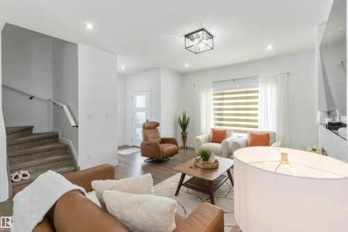 Open-concept living space featuring wood-finish flooring, recessed lighting, and a modern ceiling fixture - 124 28 Street, Edmonton, AB 