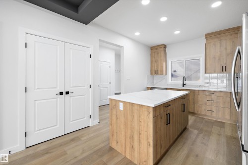 Contemporary kitchen featuring light wood-finish cabinetry, a central island with a white countertop, and recessed ceiling lighting - 954 Elderberry Landing, Edmonton, AB - Indoor Photo Showing Kitchen