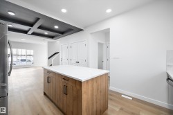 Central kitchen island with wood-finish cabinetry and a white countertop - 