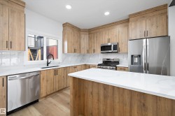 Contemporary kitchen featuring light wood-finish cabinetry, white countertops, and a full suite of stainless steel appliances - 