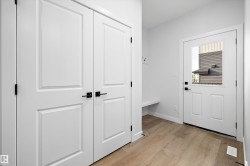 Entryway featuring a built-in bench, coat hooks, and wood-finish flooring - 