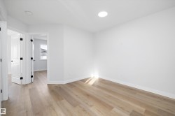 Spacious room featuring wood-finish flooring, recessed ceiling lighting, and crisp white walls - 