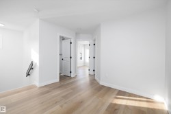 Bright interior space featuring light wood-finish flooring, crisp white walls, and contemporary baseboards - 