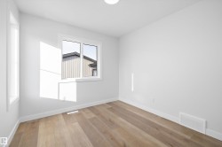 Spacious room featuring wood-finish flooring, white baseboards, and bright white walls - 