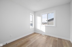 Bright room with wood-finish flooring, white baseboards, and two windows with white trim - 