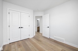 Interior room featuring light wood-finish flooring and white baseboards - 