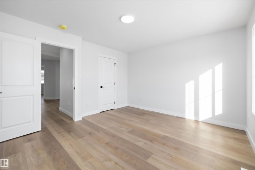 Spacious room featuring wood-finish flooring, white walls, and bright overhead lighting - 954 Elderberry Landing, Edmonton, AB - Indoor Photo Showing Other Room