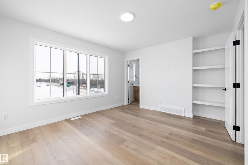 Bright interior space featuring wood-finish flooring and a large multi-pane window - 954 Elderberry Landing, Edmonton, AB - Indoor Photo Showing Other Room