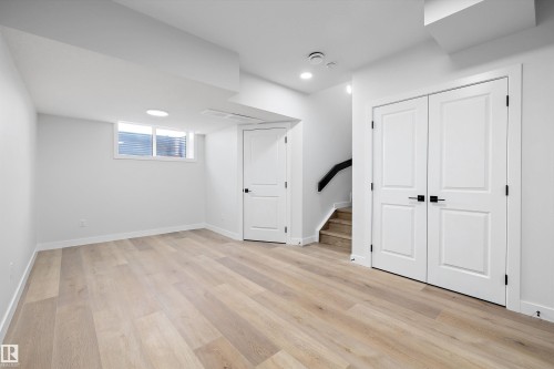 Spacious room featuring light wood-finish flooring, white walls, and a large egress window - 954 Elderberry Landing, Edmonton, AB - Indoor Photo Showing Other Room