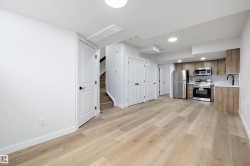 Open-concept living space featuring wood-finish flooring, recessed lighting, and a modern kitchen with stainless steel appliances - 