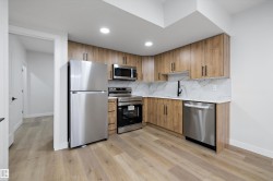 Modern kitchen featuring wood-look cabinetry, stainless steel appliances, and a marble-patterned backsplash - 