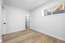 Neutral interior space featuring light wood-finish flooring, white walls, and a window with white trim - 