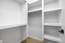 Custom closet organization system featuring white shelving and a hanging rod - 