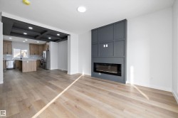 Spacious living area featuring wood-finish flooring, recessed lighting, and a modern built-in fireplace with a paneled accent wall - 