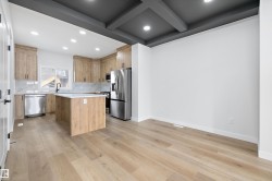 Contemporary kitchen featuring light wood-finish cabinetry, stainless steel appliances, a center island with white countertop, and recessed lighting - 