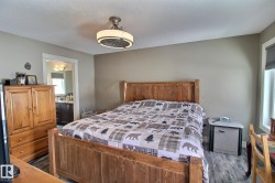 This room features a wooden bed frame, a ceiling light fixture, and a window with blinds - 
