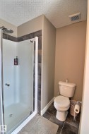The bathroom features a standing shower with a glass enclosure and a toilet - 