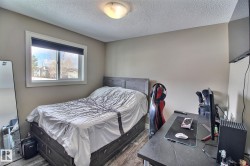 Bedroom featuring light-colored walls, a window with a view of the outdoors, and textured flooring - 