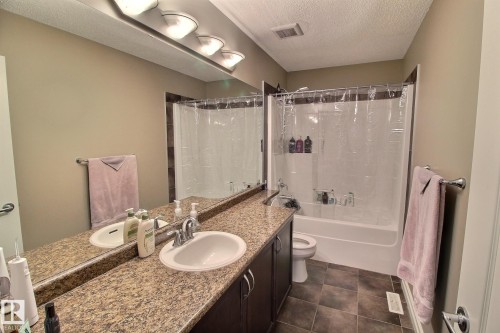 Bathroom featuring a double vanity with an expansive countertop, a large mirror, and a combination bathtub and shower with a clear shower curtain - 1212 Westerra Crescent, Stony Plain, AB - Indoor Photo Showing Bathroom