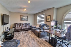 Spacious room featuring wood-style flooring, neutral-toned walls, and a large arched window with blinds - 