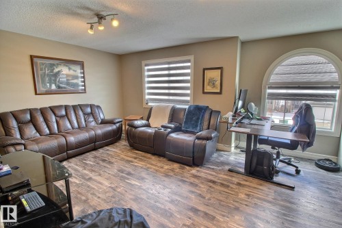 This living area features durable flooring, a track lighting fixture, and a large arched window with blinds - 1212 Westerra Crescent, Stony Plain, AB - Indoor Photo Showing Living Room