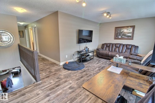 The property features wood-look flooring throughout the main areas, complemented by light-colored walls and white baseboards - 1212 Westerra Crescent, Stony Plain, AB - Indoor Photo Showing Living Room