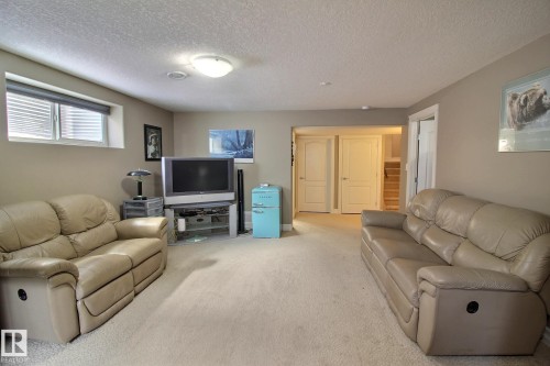 This inviting living area features carpeted floors, light beige walls, and a window with horizontal blinds - 1212 Westerra Crescent, Stony Plain, AB - Indoor