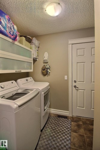 Dedicated laundry room featuring tile flooring and overhead cabinetry - 1212 Westerra Crescent, Stony Plain, AB - Indoor Photo Showing Laundry Room