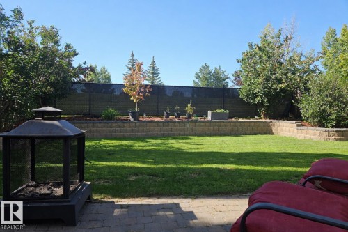 The property features an extensive yard with a well-maintained lawn and a paved patio area - 1212 Westerra Crescent, Stony Plain, AB - Outdoor With Backyard