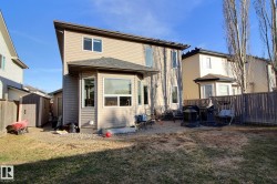 Two-story residence with beige siding exterior and contrasting dark roofing - 