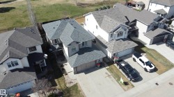 Two-story residential property featuring a gray shingle roof, attached two-car garage, concrete driveway, and a front walkway - 