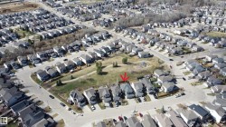 Aerial view of a residential neighborhood with detached homes, paved streets, and green spaces - 