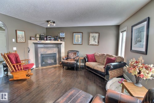 Living room featuring dark hardwood floors, a fireplace with a tile surround and mantel, and painted walls - 1212 Westerra Crescent, Stony Plain, AB - Indoor Photo Showing Living Room With Fireplace