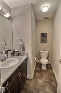 The bathroom features a vanity with a light gray speckled countertop, a white oval sink with a chrome faucet, and a dark wood cabinet below - 