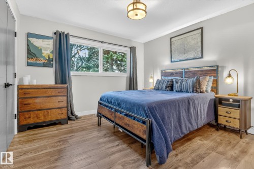 This room features light wood-style flooring, a large window with drapes, and light-colored walls - 7408 92 Avenue, Edmonton, AB - Indoor Photo Showing Bedroom