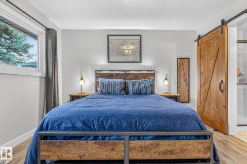 This bedroom features light-colored walls, a window providing natural light, and wood-look flooring - 7408 92 Avenue, Edmonton, AB - Indoor Photo Showing Bedroom