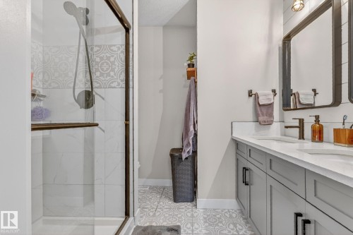 This bathroom features a double vanity with light gray cabinetry and white countertops, complemented by two framed mirrors - 7408 92 Avenue, Edmonton, AB - Indoor Photo Showing Bathroom