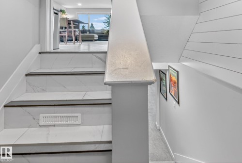 The property features an interior staircase with white tiled steps and dark treads, complemented by white walls - 7408 92 Avenue, Edmonton, AB - Indoor Photo Showing Other Room