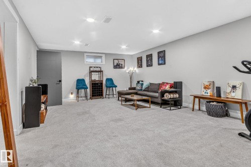 Spacious recreation room featuring light gray carpeting, recessed lighting, and a large window providing natural light - 7408 92 Avenue, Edmonton, AB - Indoor