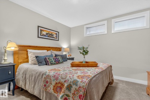 This room features light grey walls, carpeted flooring, and two high windows providing natural illumination - 7408 92 Avenue, Edmonton, AB - Indoor Photo Showing Bedroom