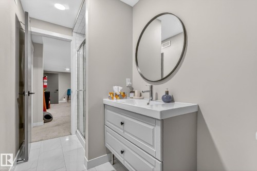 Bathroom featuring a vanity with two drawers, a rectangular sink, and a round mirror with a dark frame - 7408 92 Avenue, Edmonton, AB - Indoor Photo Showing Bathroom