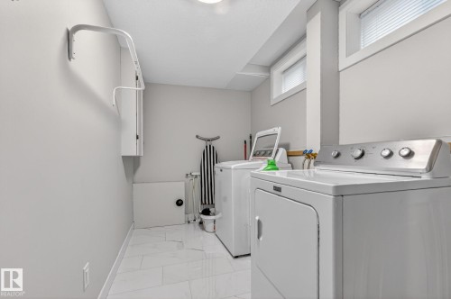 The laundry area features white tile flooring, white appliances, and a wall-mounted drying rack - 7408 92 Avenue, Edmonton, AB - Indoor Photo Showing Laundry Room