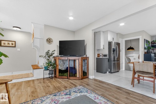 The interior living space features wood flooring, a recessed ceiling light, and a dedicated area for entertainment - 7408 92 Avenue, Edmonton, AB - Indoor