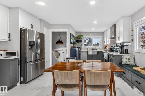 The kitchen features white upper cabinetry, gray lower cabinetry, and stainless steel appliances - 7408 92 Avenue, Edmonton, AB - Indoor