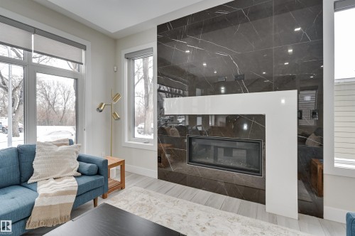 Contemporary fireplace featuring a black marble-look surround with white accent trim - 9741 90 Avenue, Edmonton, AB - Indoor Photo Showing Living Room With Fireplace